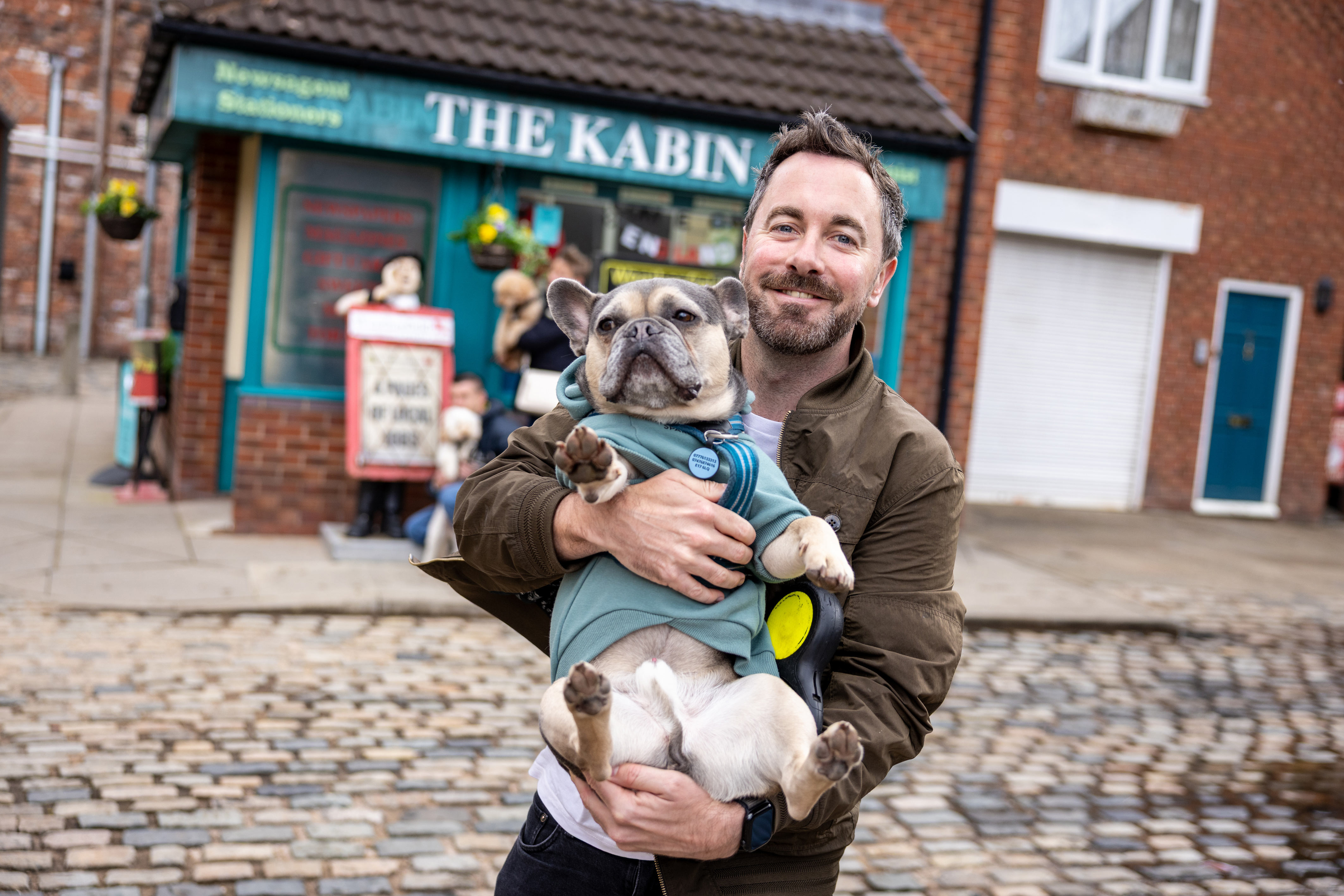 A visitor carrying his dog at the Walkies in Weatherfield event at the Coronation Street Experience