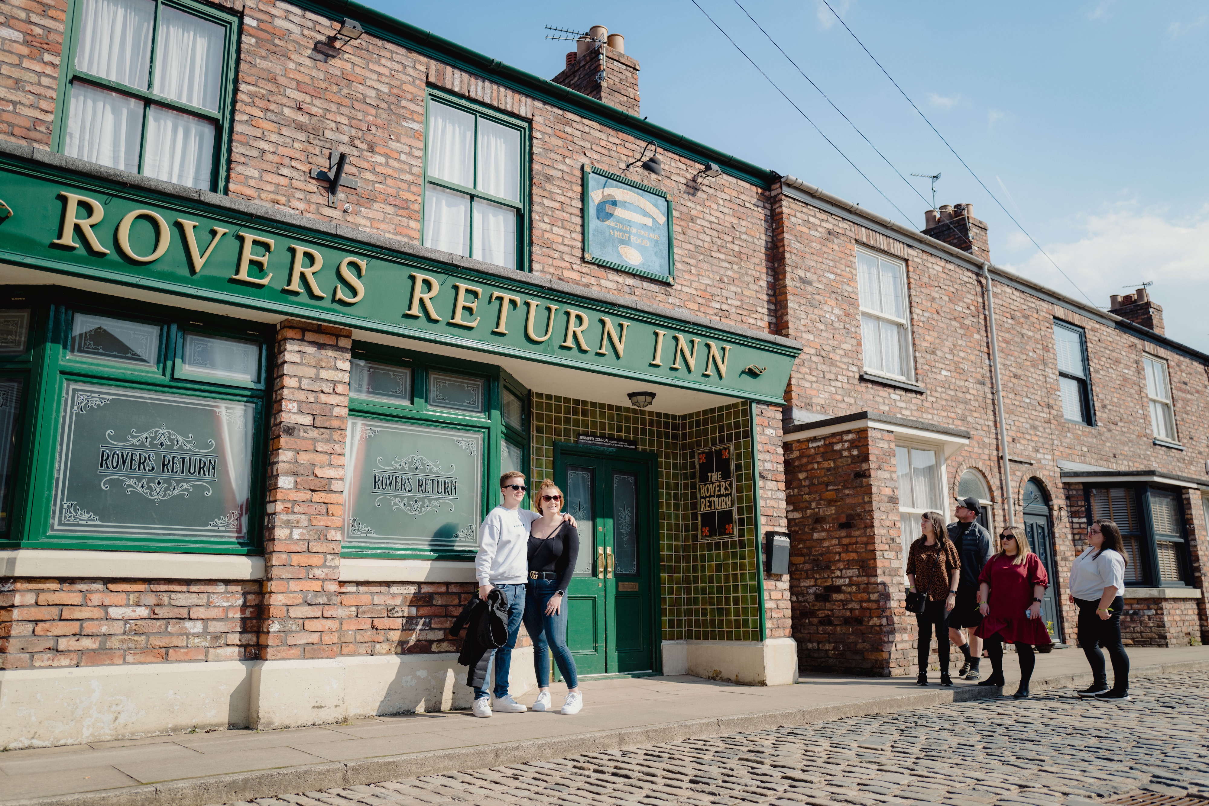 A couple posing for a photo in front of Rovers Return at the Coronation Street Experience