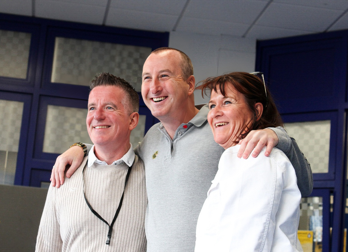 Happy visitors on the Coronation Street Star Tour posing for a photo with Andrew Whyment, who plays Kirk Sutherland