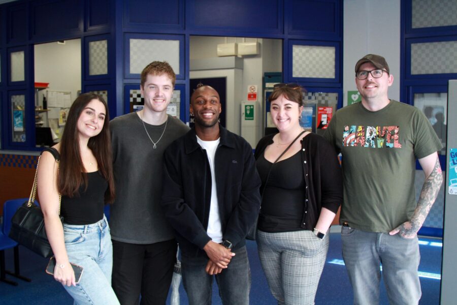 Ryan Russell, who plays Michael Bailey, posing for a photograph with four young guests at the Coronation Street Tour.