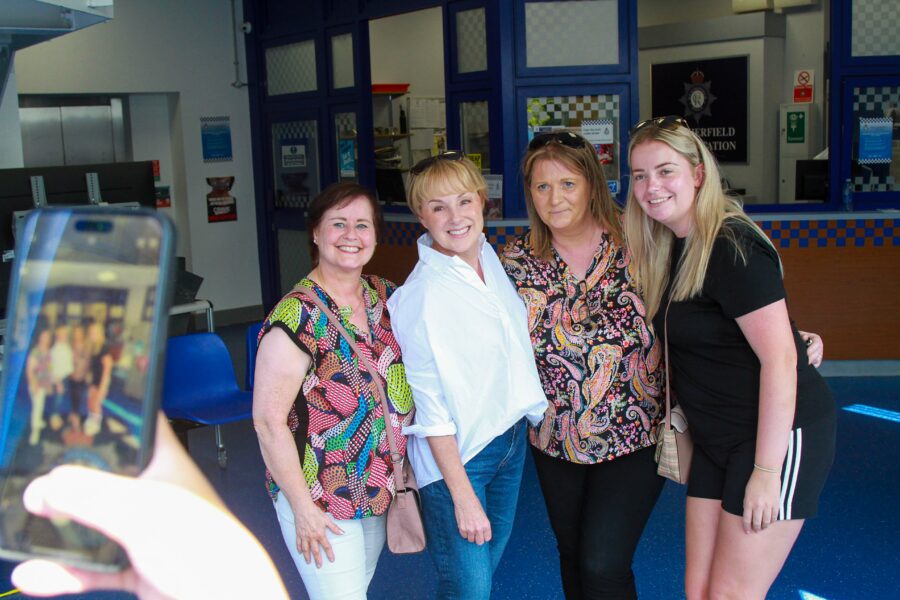 Sally Dynevor smiling and posing with guests as they capture the moment on their phone during the Coronation Street Experience tour.